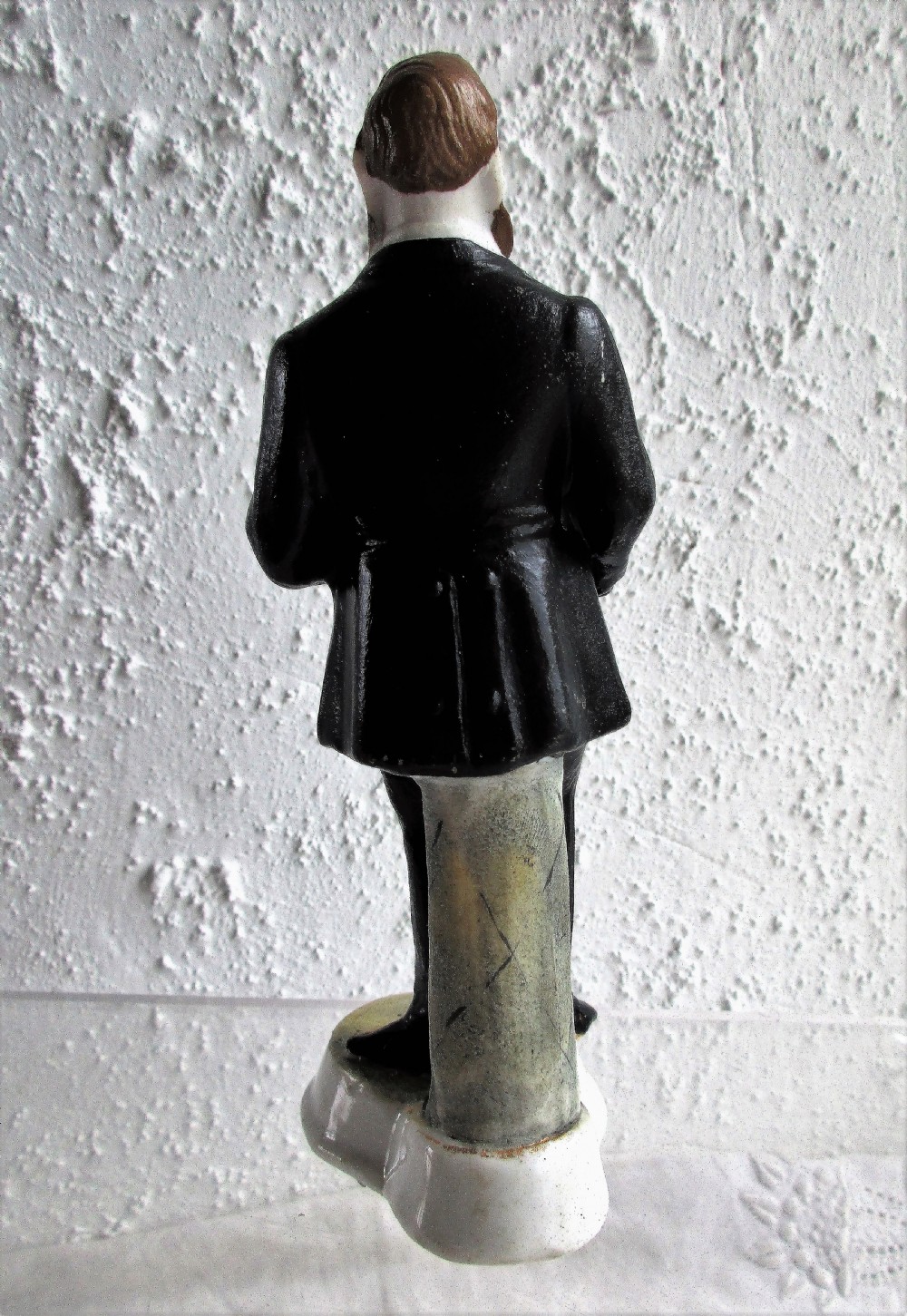 An antique Victorian porcelain figurine depicting a standing man in a black frock coat and bow tie on a round white base inscribed Mr Sankey. View III