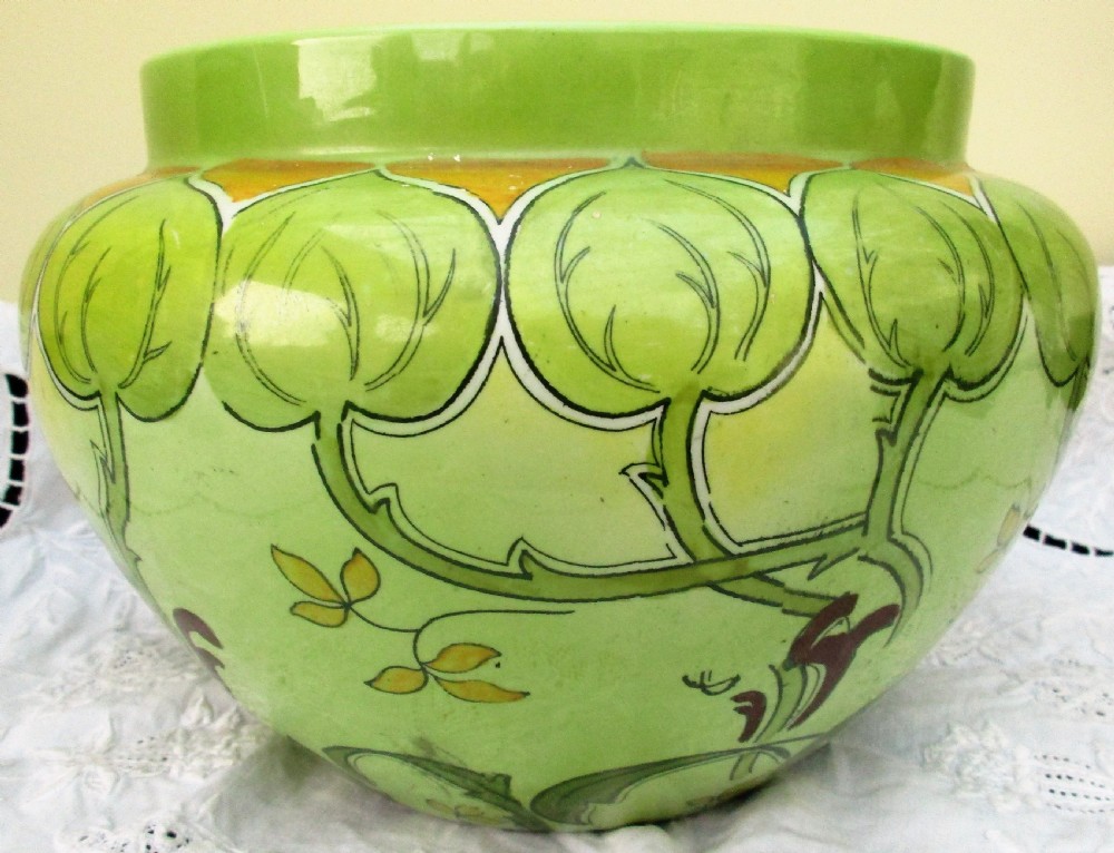 An antique Art Nouveau glazed ceramic jardiniere featuring a vibrant green ground decorated with stylized botanical leaf motifs and yellow accents. View III