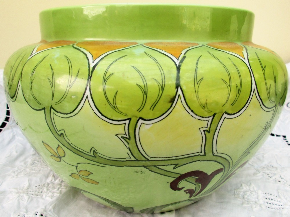 An antique Art Nouveau glazed ceramic jardiniere featuring a vibrant green ground decorated with stylized botanical leaf motifs and yellow accents. View V