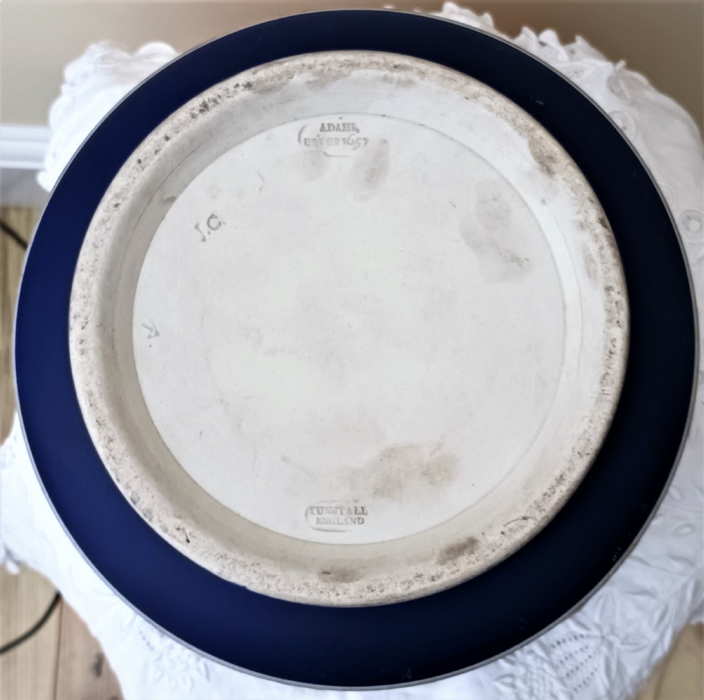 A cobalt blue ceramic jasperware jardiniere decorated with white raised relief scenes of a traditional hunt surrounded by foliage and a leaf band along the rim. View V