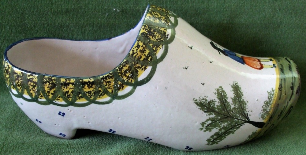An antique French Quimper faience ceramic sabot shoe featuring a hand-painted Breton figure and green patterned border against a cream glaze background. View II