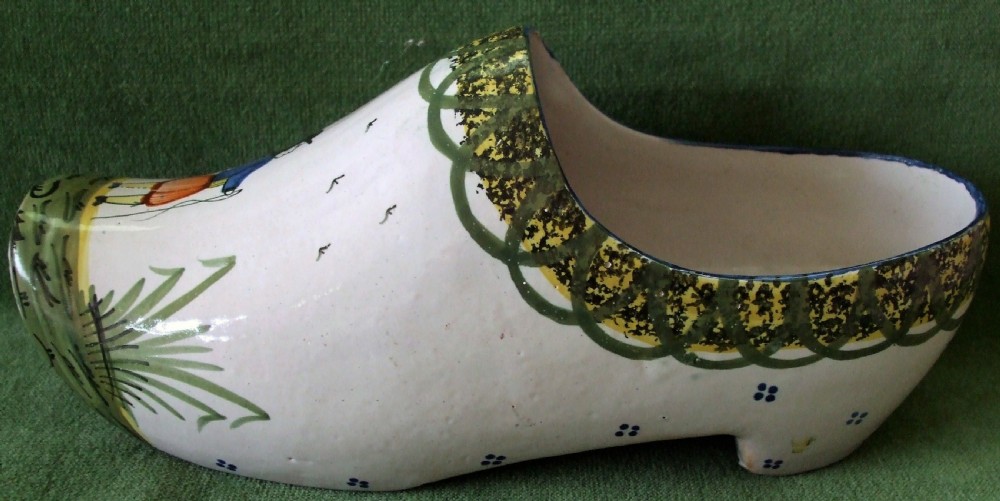 An antique French Quimper faience ceramic sabot shoe featuring a hand-painted Breton figure and green patterned border against a cream glaze background. View IV