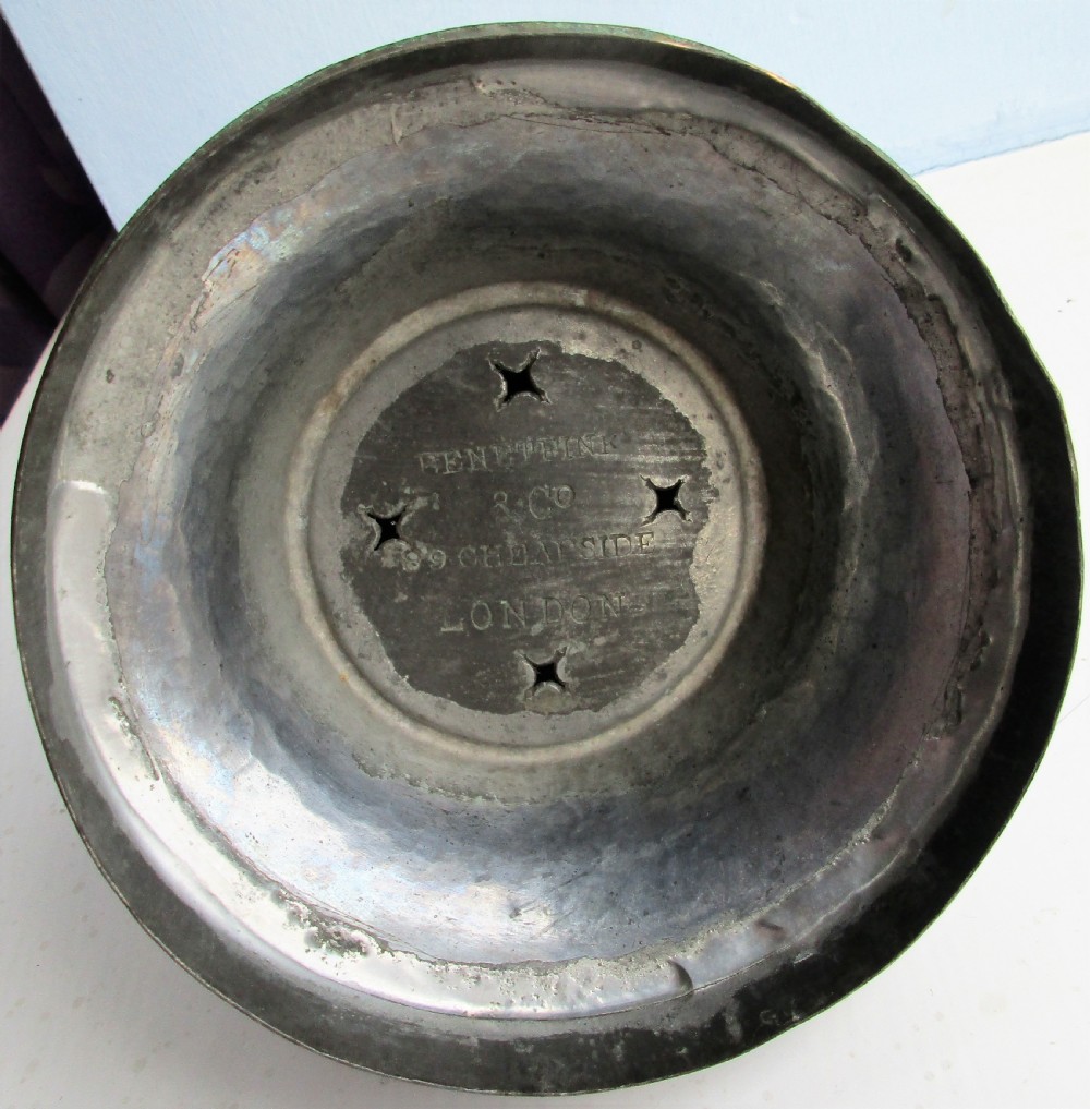 A dark patinated metal Victorian tea urn featuring a bulbous body, twin side handles, a front spigot with a white handle, and a pointed lid. View IX