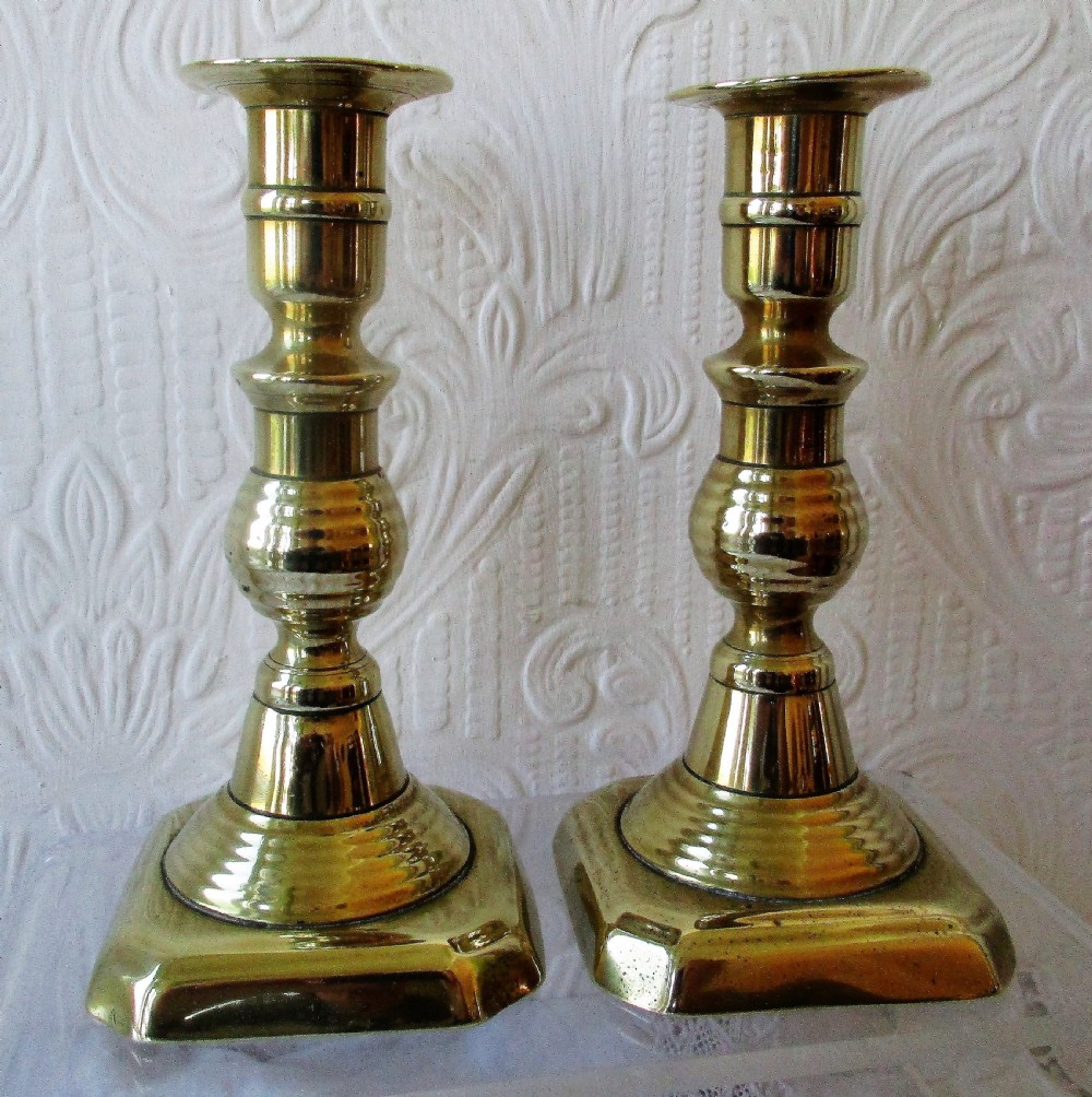 A pair of turned Victorian brass candlesticks featuring baluster stems and square bases. View II