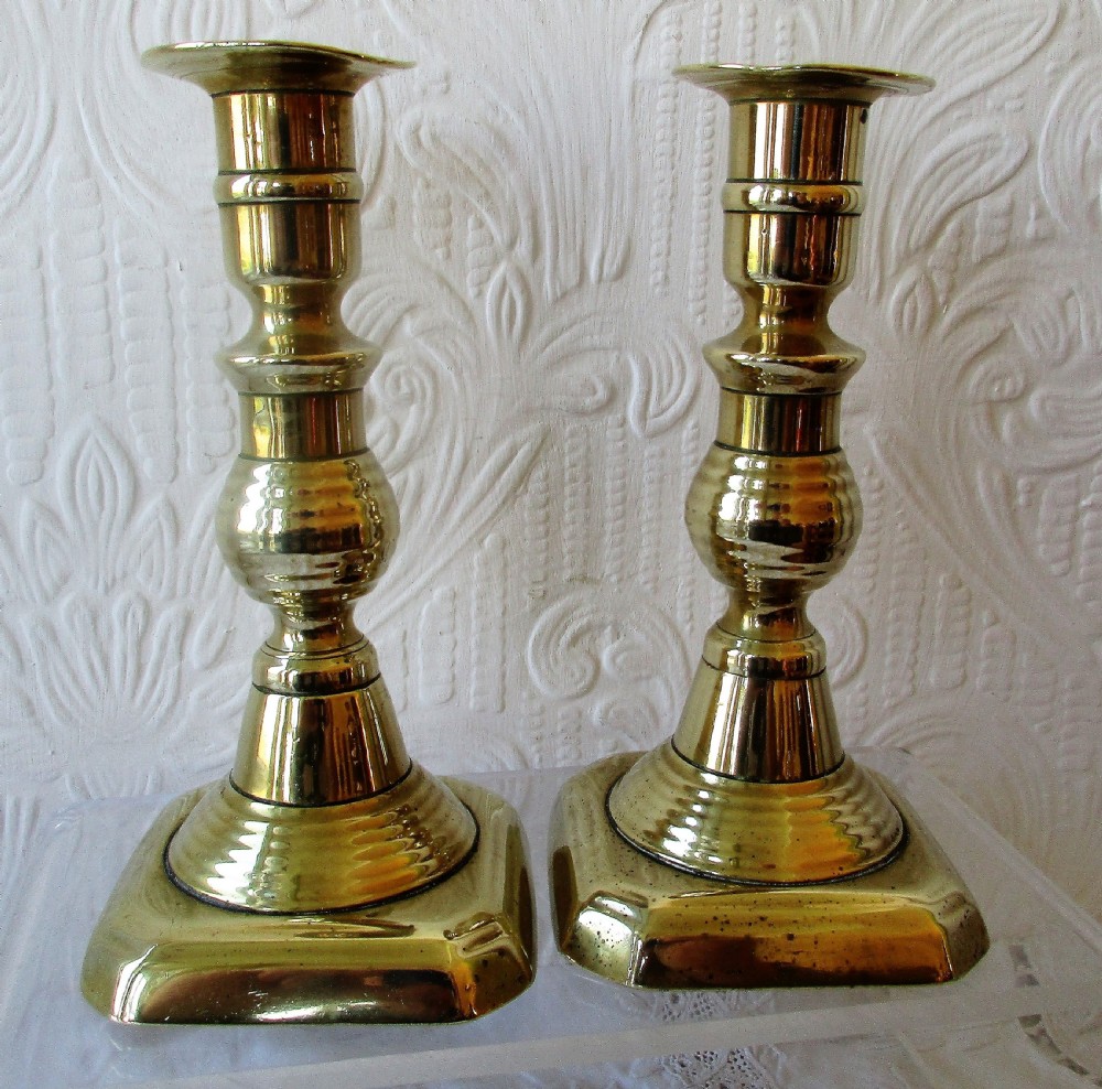 A pair of turned Victorian brass candlesticks featuring baluster stems and square bases. View III
