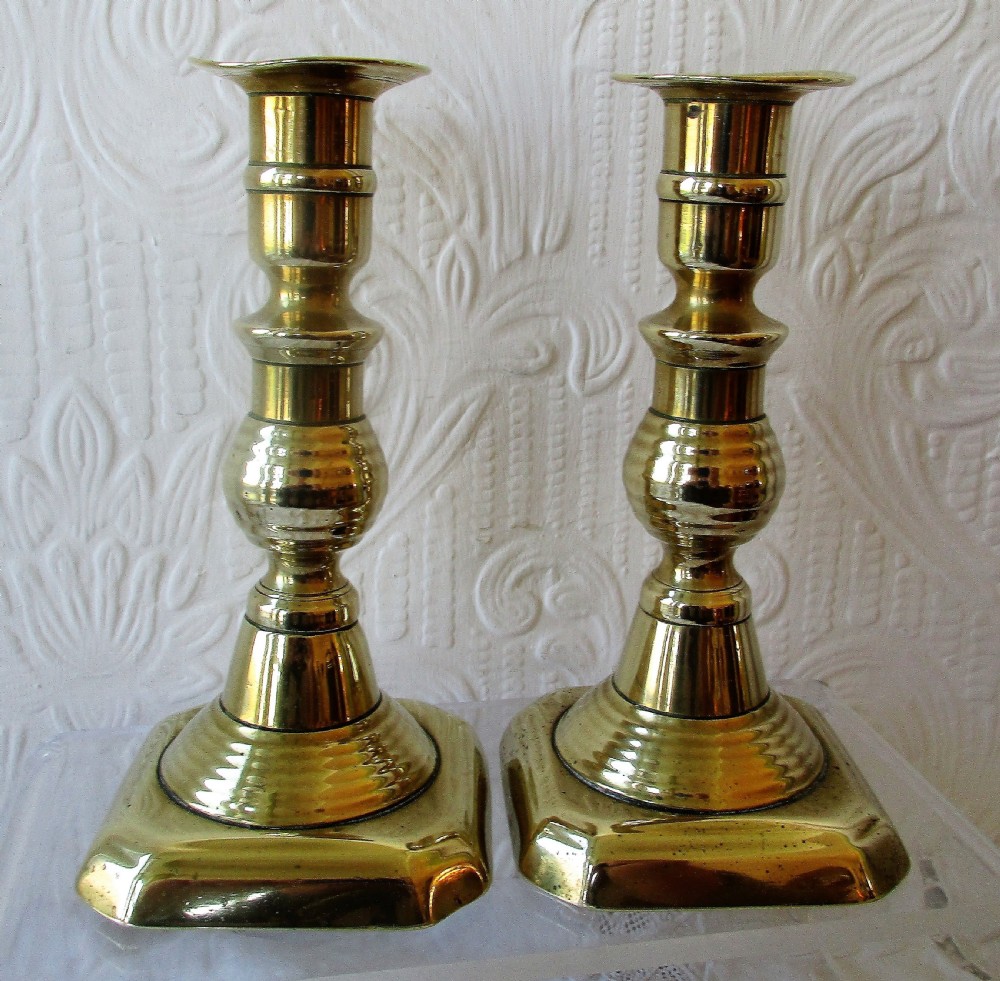 A pair of turned Victorian brass candlesticks featuring baluster stems and square bases. View IV