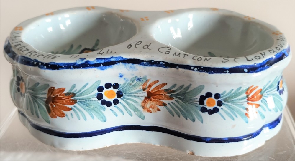 A double salt cellar made of pale blue tin-glazed ceramic with hand-painted floral motifs in blue, green, and orange.