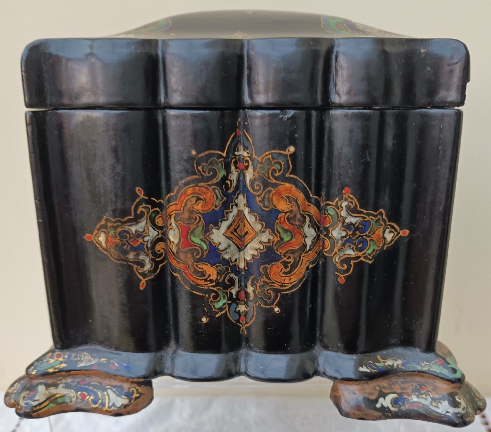 A Victorian black lacquered papier-mache tea caddy featuring a lobed serpentine body, central polychrome arabesque motif, and brass escutcheon on gilded feet. View II