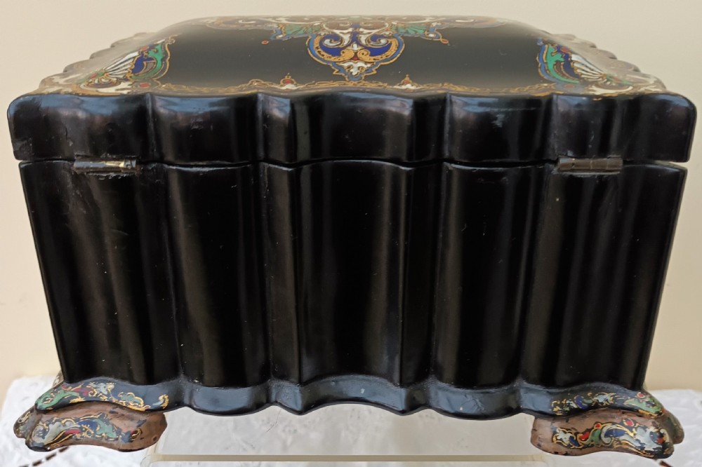 A Victorian black lacquered papier-mache tea caddy featuring a lobed serpentine body, central polychrome arabesque motif, and brass escutcheon on gilded feet. View III