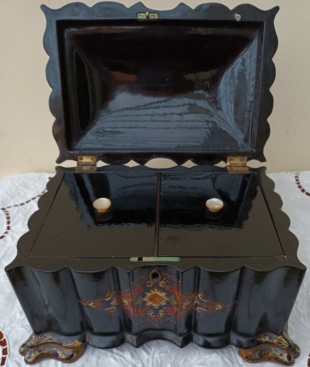 A Victorian black lacquered papier-mache tea caddy featuring a lobed serpentine body, central polychrome arabesque motif, and brass escutcheon on gilded feet. View VIII