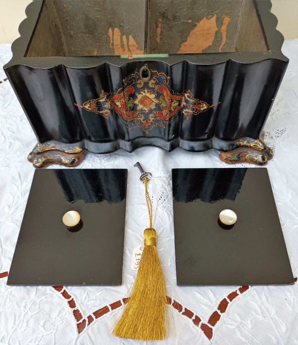 A Victorian black lacquered papier-mache tea caddy featuring a lobed serpentine body, central polychrome arabesque motif, and brass escutcheon on gilded feet. View XI