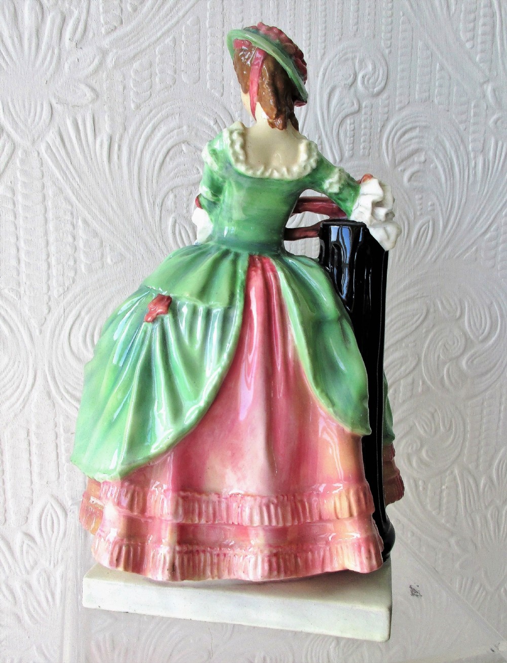 A vintage Royal Doulton porcelain figurine titled Kate Hardcastle depicting a woman in an 18th-century style green overskirt and pink ruffled dress. View III