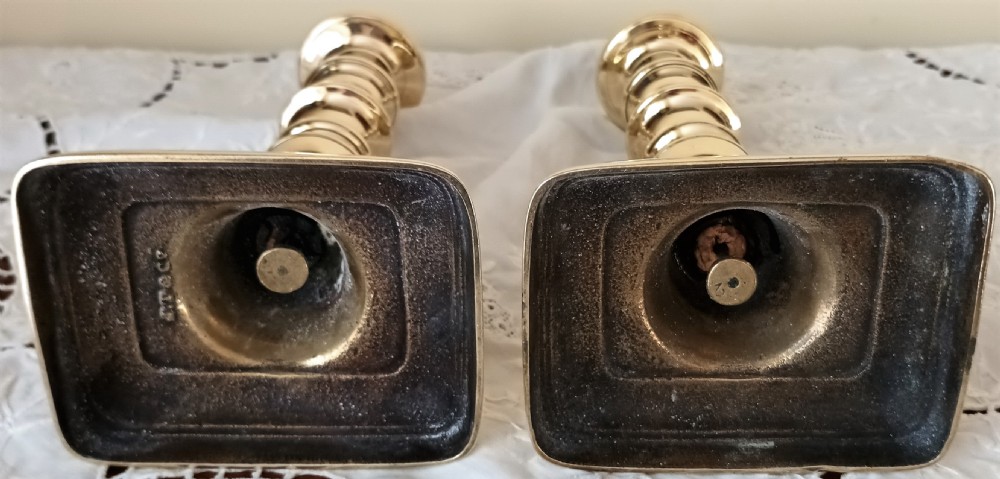 A pair of polished Georgian brass candlesticks featuring turned knopped stems on stepped square bases. View VI