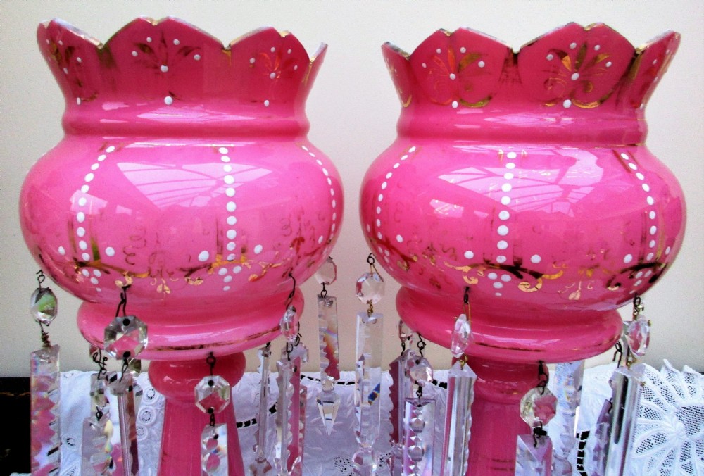 A pair of Victorian pink glass lustres decorated with gilded scrolling, enamel dots, scalloped rims, and suspended clear cut-glass prisms. View IV