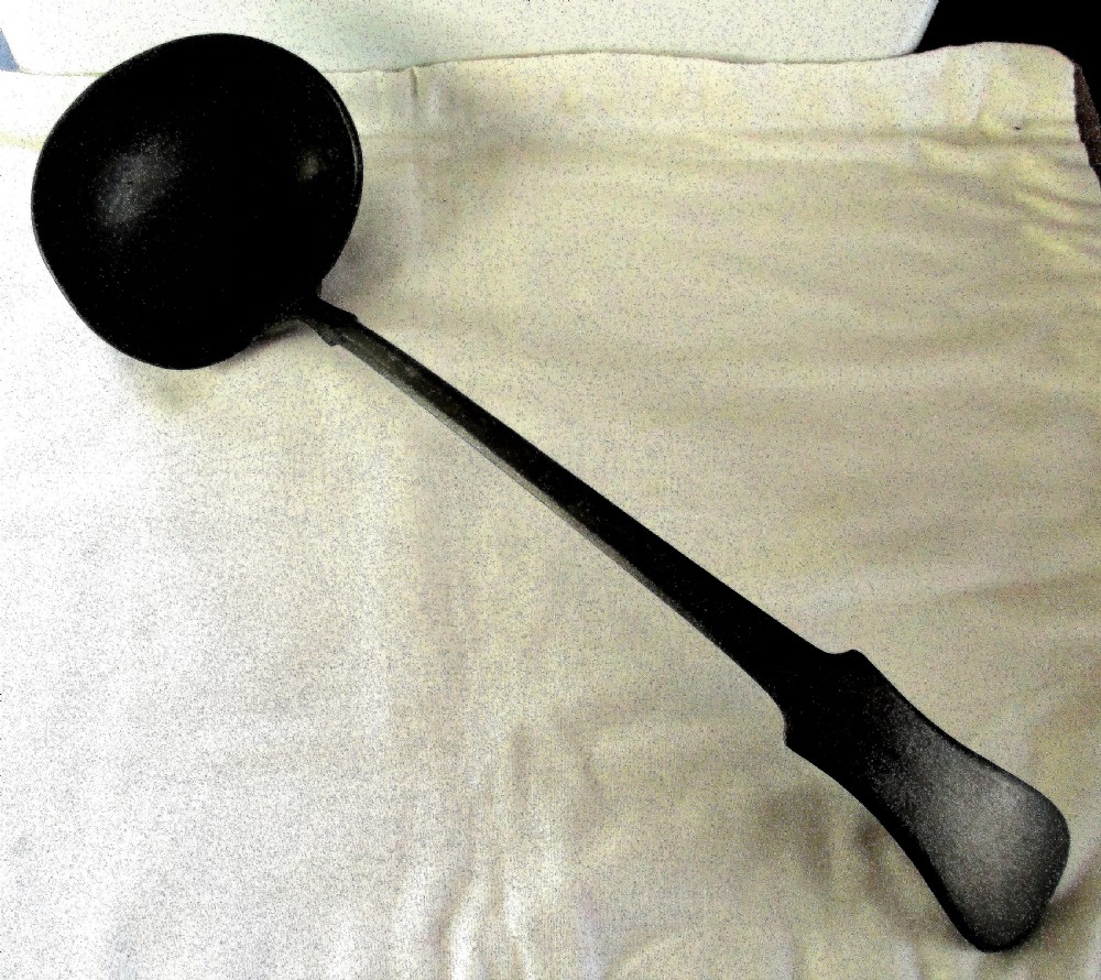 An antique Georgian pewter ladle featuring a rounded deep bowl and a long flattened handle stem.