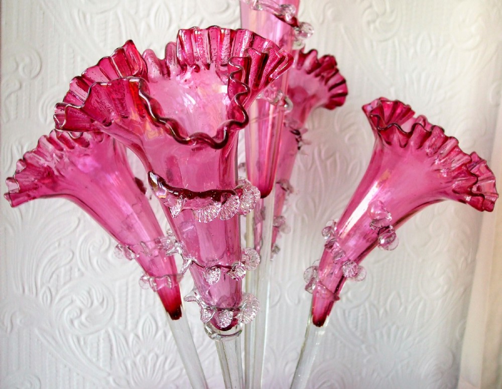 A Victorian cranberry glass epergne featuring a ruffled base bowl and four flared trumpet vases detailed with clear glass trailing. View III
