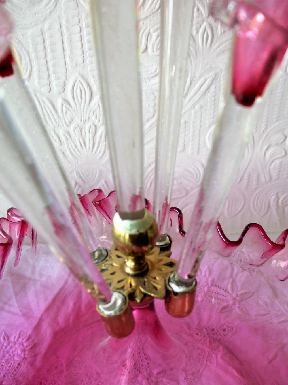 A Victorian cranberry glass epergne featuring a ruffled base bowl and four flared trumpet vases detailed with clear glass trailing. View V