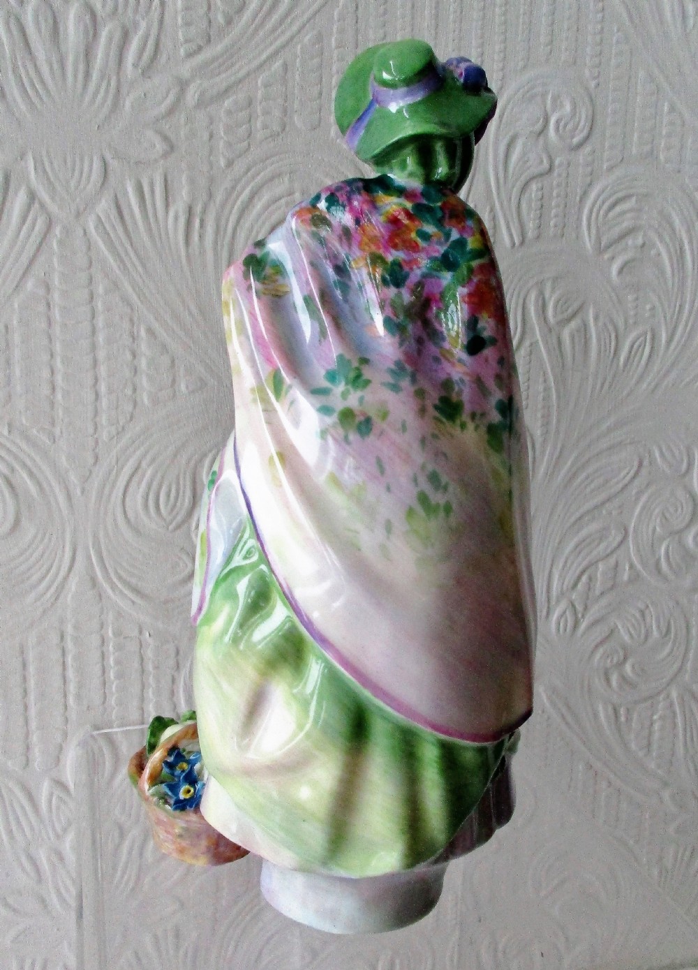 A hand-painted Royal Doulton bone china figurine depicting a female figure in a green bonnet and floral patterned cloak. View III