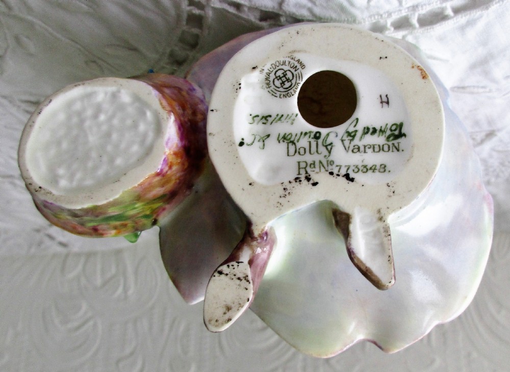 A hand-painted Royal Doulton bone china figurine depicting a female figure in a green bonnet and floral patterned cloak. View V