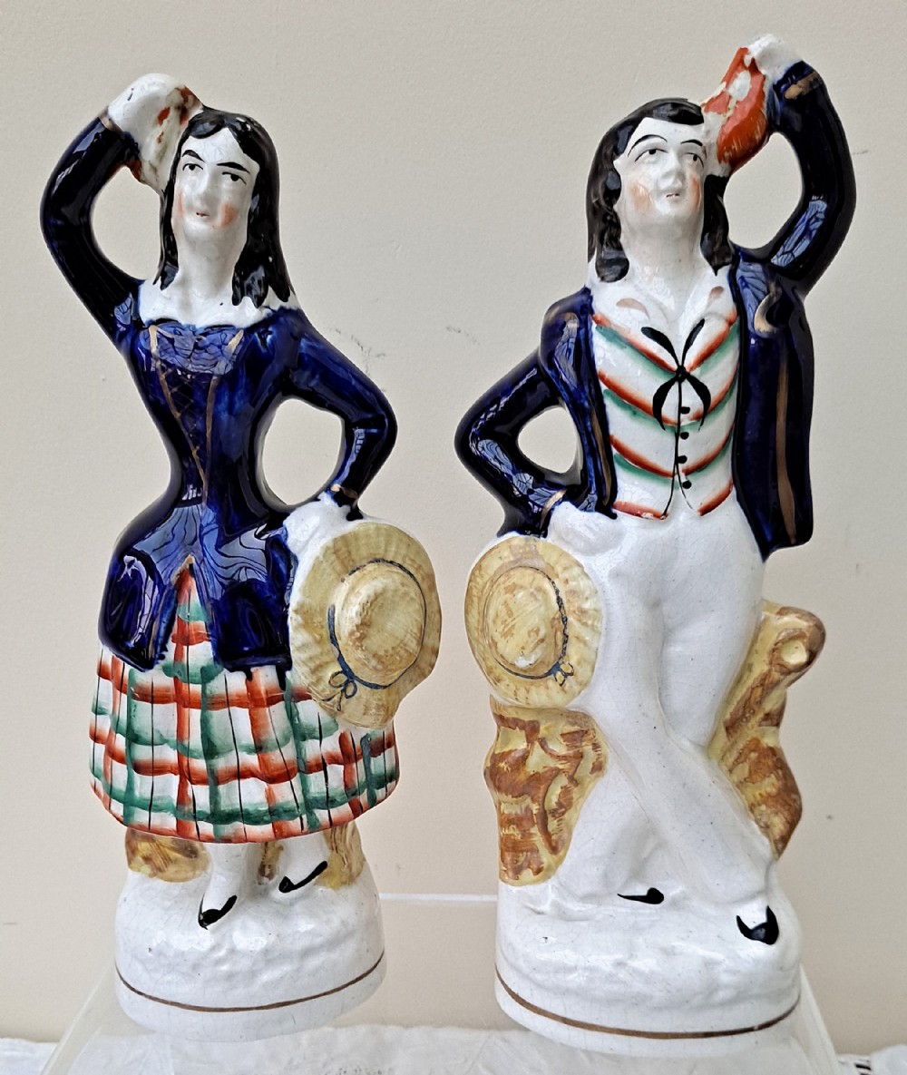 A pair of Victorian Staffordshire earthenware figures depicting a male sailor and a female companion wearing cobalt blue jackets.