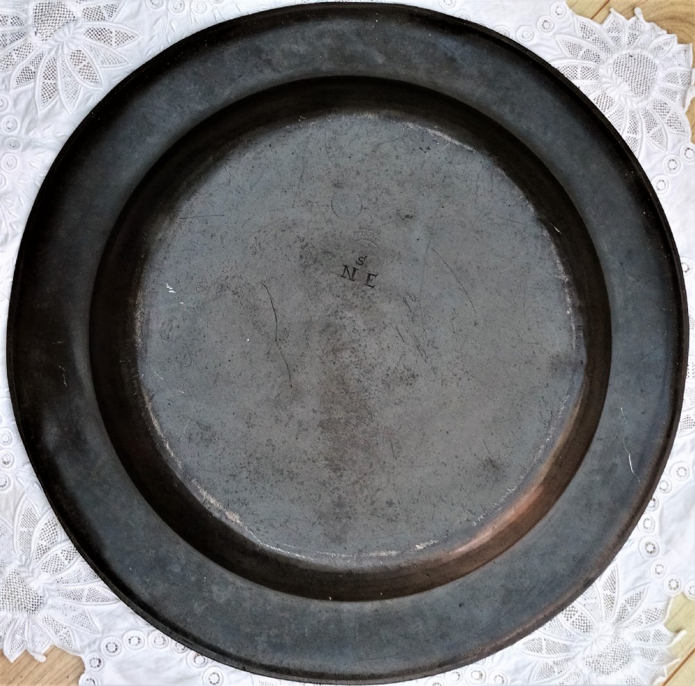 A circular Georgian pewter charger dish featuring a broad flat rim, shallow well, and dark grey patinated metal surface. View IV