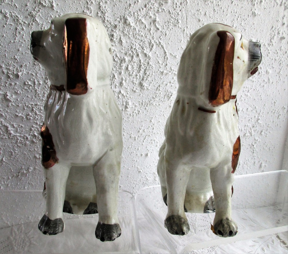 A pair of seated antique Victorian Staffordshire pottery spaniel dog figurines with white glazed bodies and painted copper lustre spots. View II