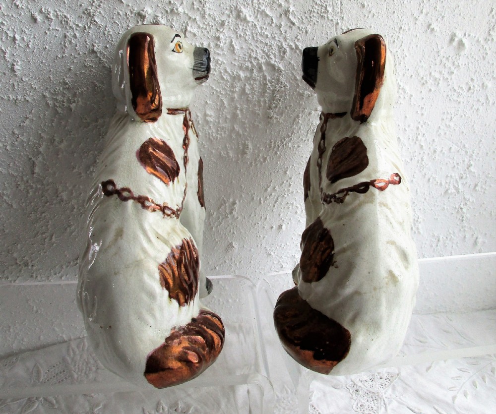 A pair of seated antique Victorian Staffordshire pottery spaniel dog figurines with white glazed bodies and painted copper lustre spots. View V