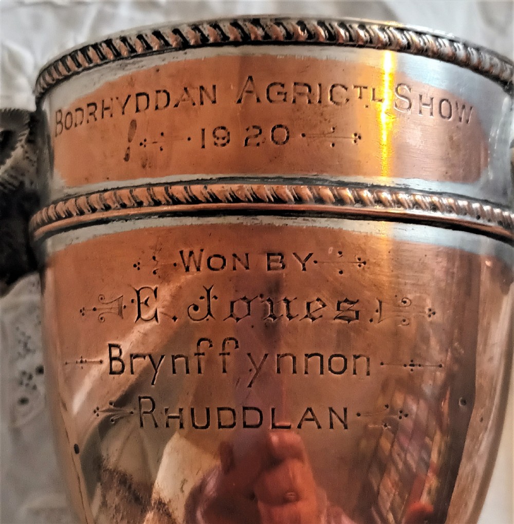 A miniature Georgian Old Sheffield Plate urn featuring a fitted lid with a finial, square base, engraved inscription, and rams head side handles. View VII