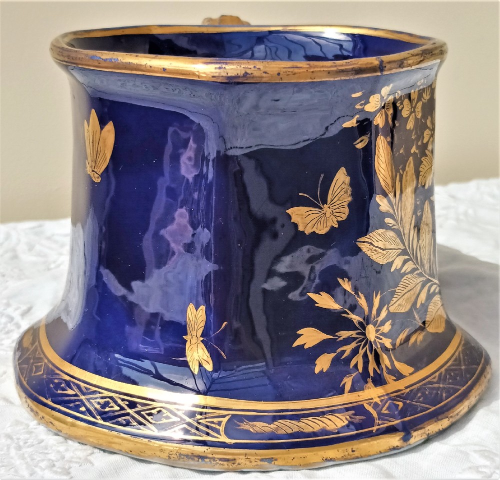 An antique cobalt blue ironstone mug featuring flared sides, a gilded scroll handle, and intricate gold floral motifs with a geometric border. View IV