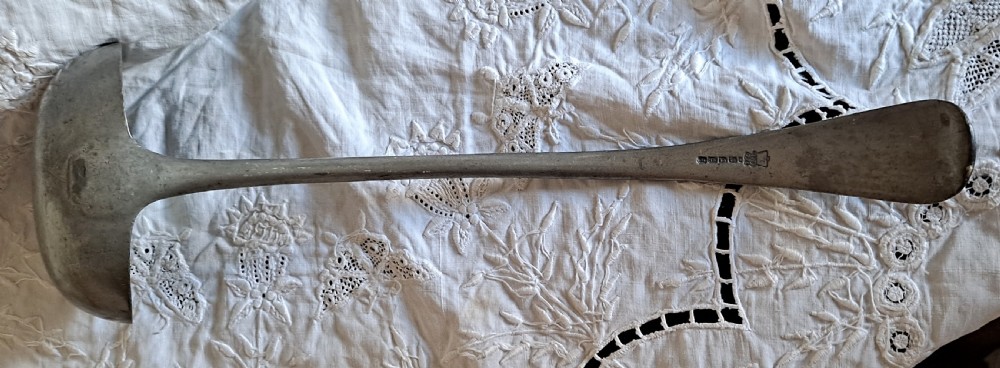An antique Victorian pewter basting ladle featuring a rounded deep bowl and an elongated flattened handle stem. View V