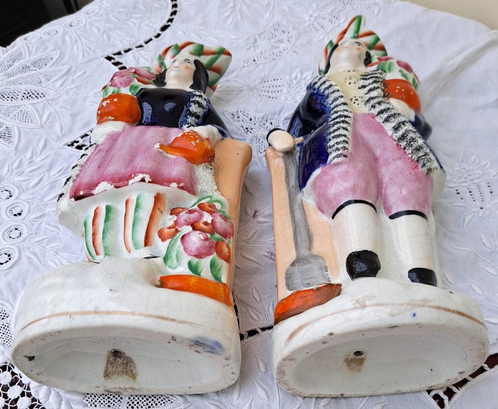 A pair of antique Victorian Staffordshire earthenware figures depicting a male and female gardener dressed in colourful attire holding flowers. View V