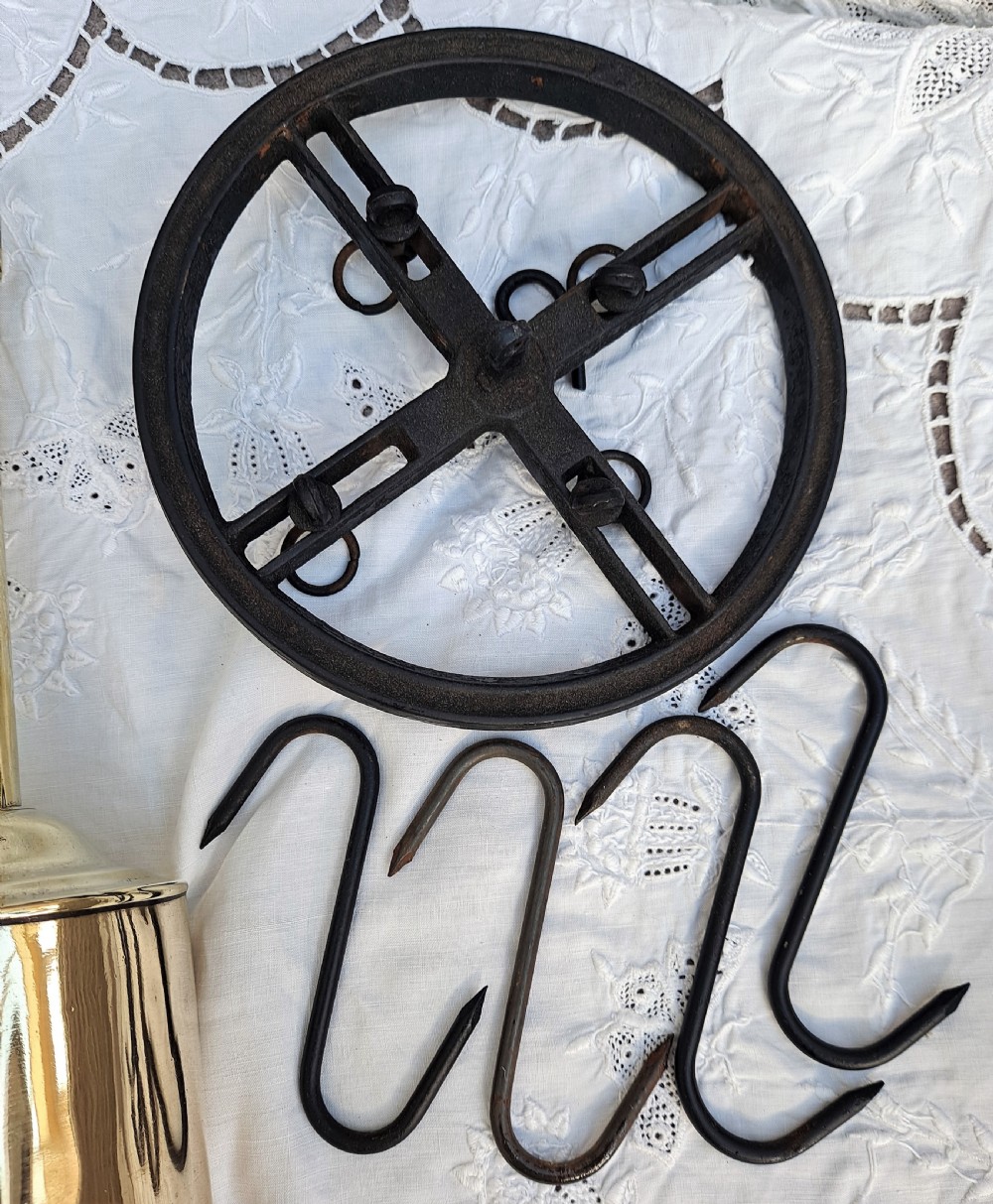 A brass bottle-shaped clockwork spit jack displayed alongside an iron mounting wheel and four wrought iron hooks. View VI