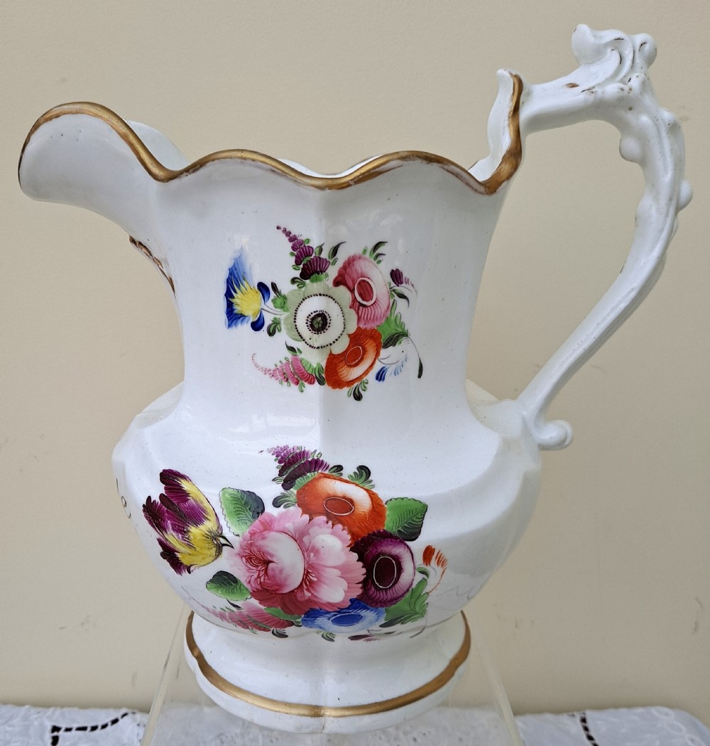 A white early Victorian porcelain jug decorated with hand-painted floral sprays and a gilded rim and handle.