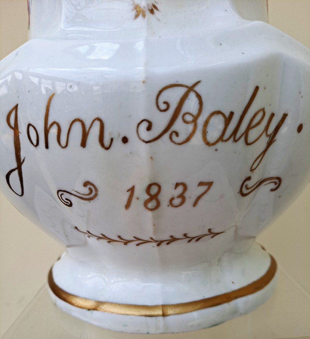 A white early Victorian porcelain jug decorated with hand-painted floral sprays and a gilded rim and handle. View V