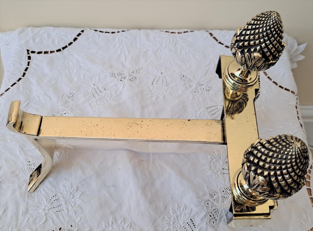 A pair of Georgian brass firedogs featuring detailed pineapple finials and tapered fluted feet. View III