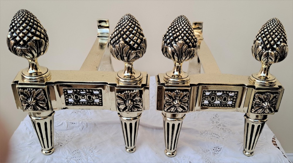 A pair of Georgian brass firedogs featuring detailed pineapple finials and tapered fluted feet. View V