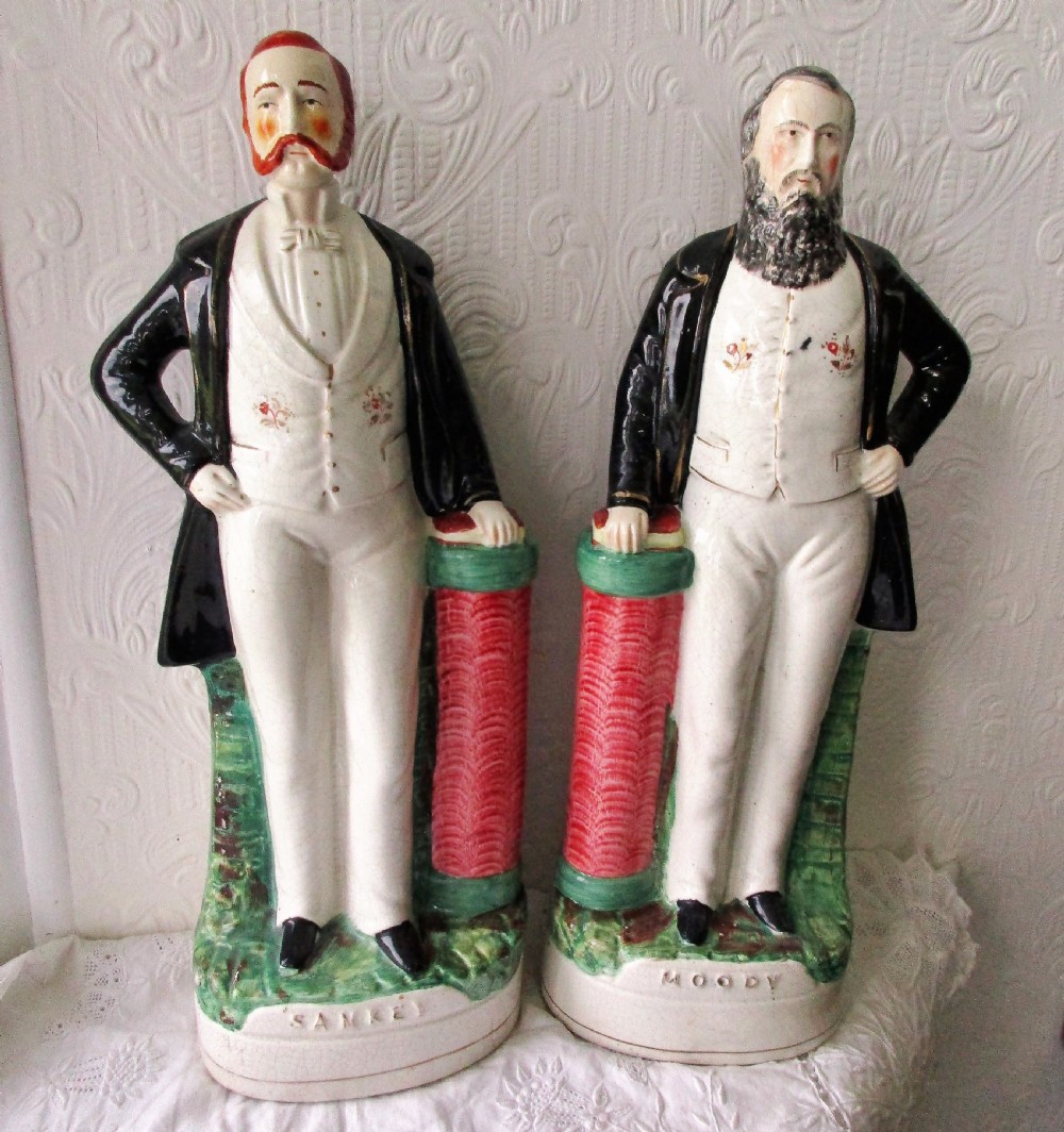 A pair of antique Victorian Staffordshire earthenware portrait figures depicting Moody and Sankey standing beside red pillars with moulded bases.
