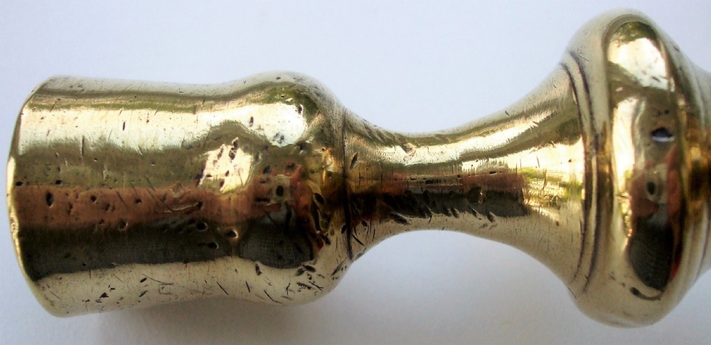A cast brass Georgian candlestick featuring a knopped central column and a shaped faceted base. View II