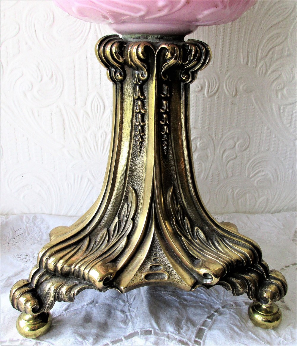 A Victorian oil lamp featuring a fluted brass column base, an embossed pink glass oil reservoir, and a ruffled cranberry glass shade. View II