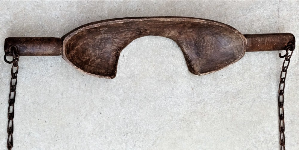 A carved dark beech wooden shoulder yoke featuring a central neck cutout and two attached iron chains with hooks. View II