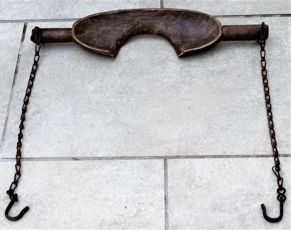 A carved dark beech wooden shoulder yoke featuring a central neck cutout and two attached iron chains with hooks. View III