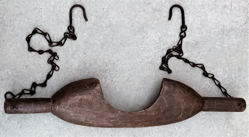 A carved dark beech wooden shoulder yoke featuring a central neck cutout and two attached iron chains with hooks. View IV
