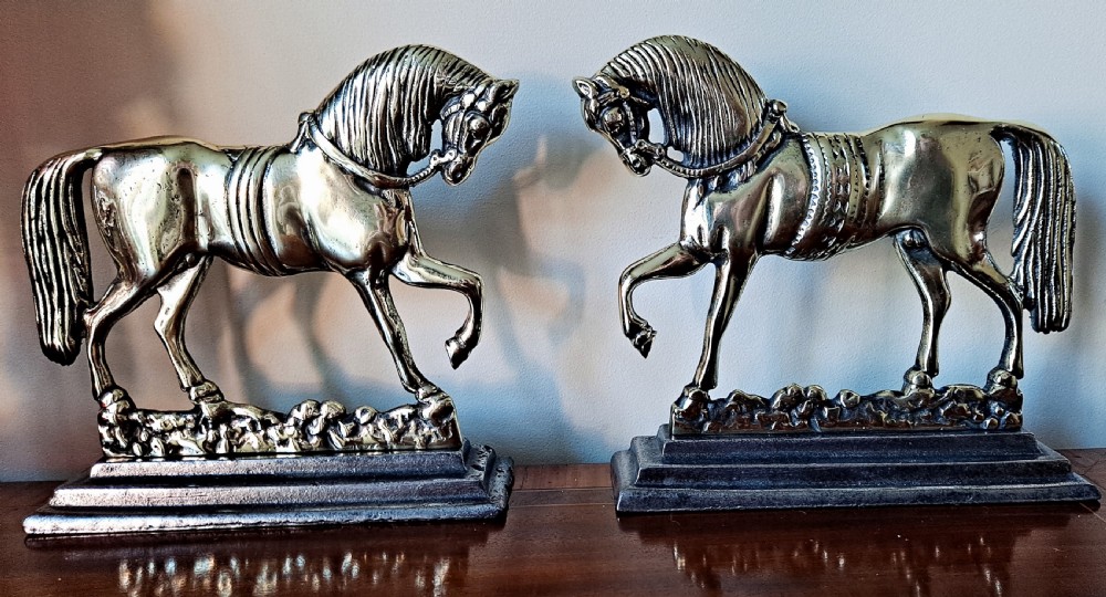 A pair of polished cast brass equestrian horses facing each other, mounted on stepped rectangular plinths. View VI