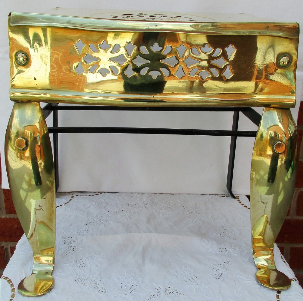 A Victorian polished brass and steel fireplace footman featuring a pierced floral apron and cabriole front legs.
