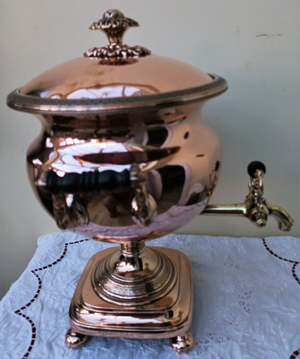 A polished Georgian copper tea urn featuring twin reeded handles, a brass spigot tap, and a square pedestal base resting on ball feet. View IV