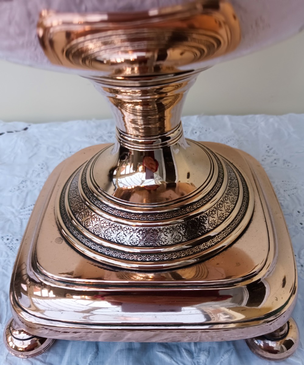 A polished Georgian copper tea urn featuring twin reeded handles, a brass spigot tap, and a square pedestal base resting on ball feet. View VII