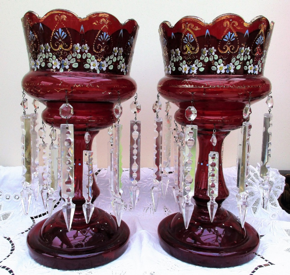 A pair of Victorian ruby red glass lustres featuring hand-painted floral enamel decoration and suspended clear cut-crystal prisms on circular bases.