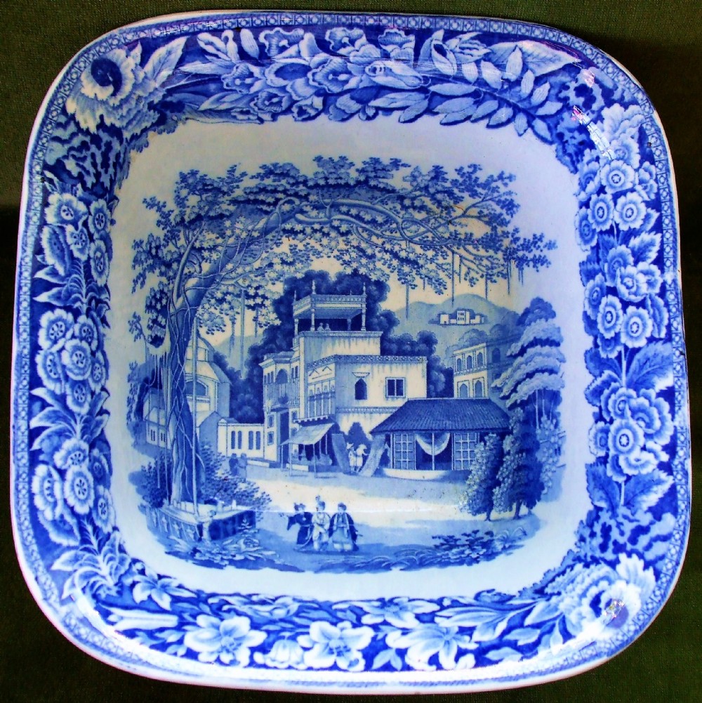 A square antique Georgian blue and white earthenware serving bowl decorated with an Eastern architectural scene and an ornate floral border.