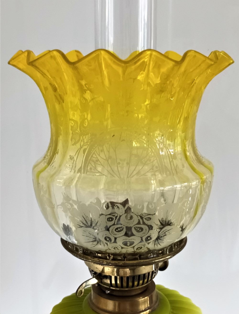 An antique Victorian oil lamp featuring a gilded metal base with sculpted cherubs, a green glass reservoir, and a yellow ruffled glass shade with chimney. View IX