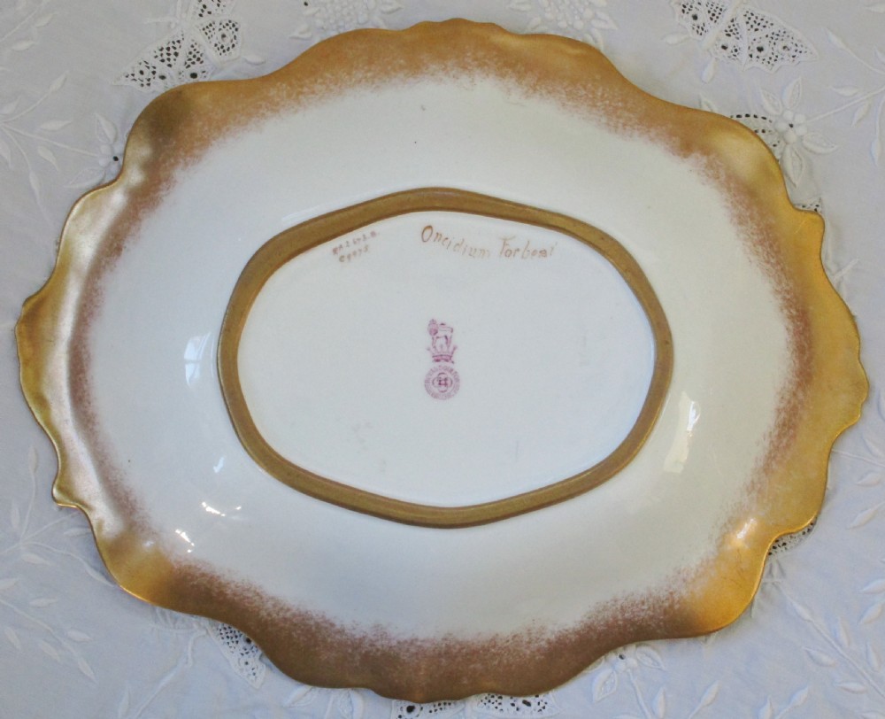 An oval antique Royal Doulton porcelain dish featuring hand-painted yellow orchids on a pale green ground with a gilded scroll border. View II